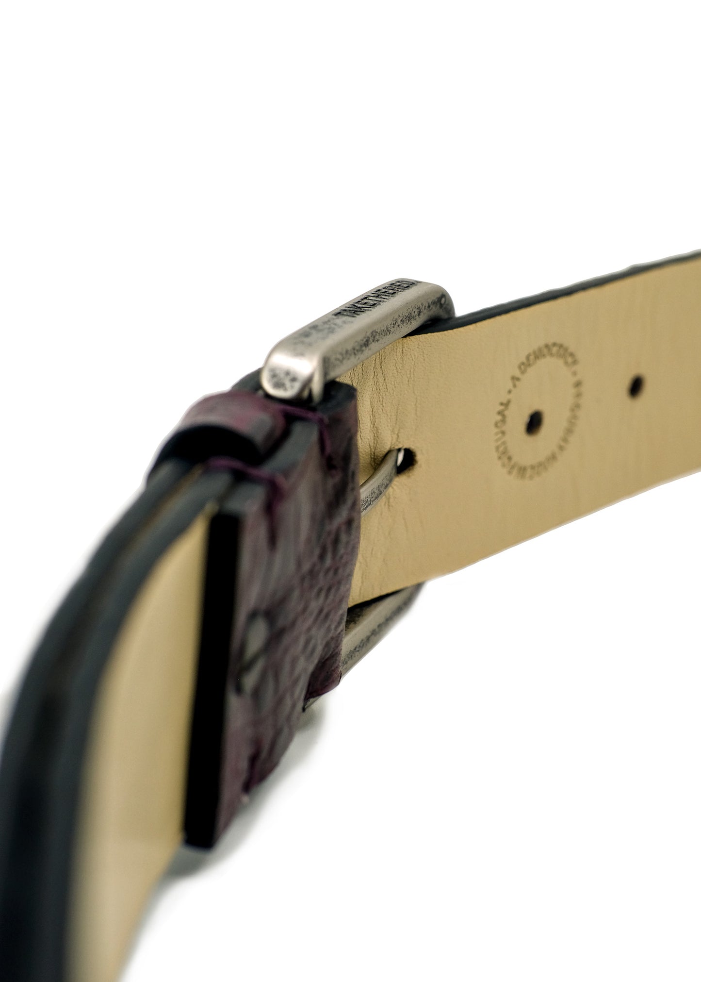 Macro shot of weathered silver buckle on Dirty Aubergine belt with engraved "TAKETHERED." branding.