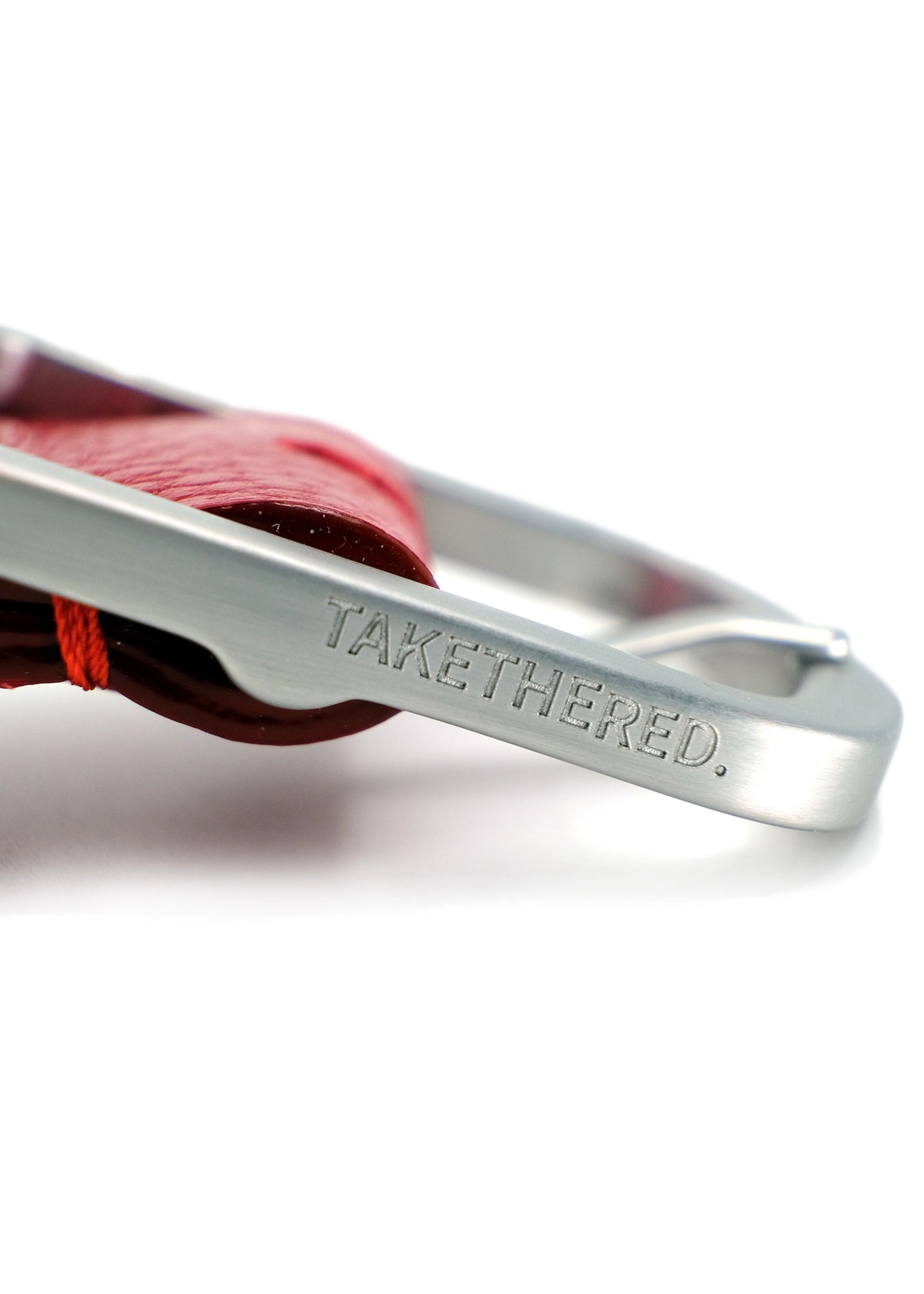Side view close-up of a weathered silver buckle engraved with "BIRD & ASH." on a red Blood Simple Grunge Belt.