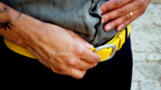 Close-up of a man's waist wearing a submarine yellow leather belt with a silver buckle embossed with Bird & Ash.