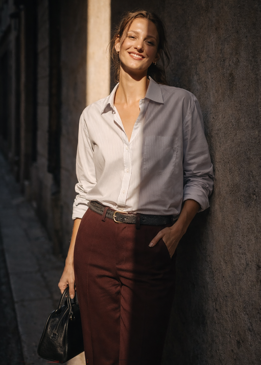 Embossed snakeskin leather belt with gold buckle, worn over white shirt and burgundy trousers.