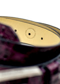Close-up of Dirty Aubergine belt interior with "Proudly Made in Portugal" circular stamp on cream leather.
