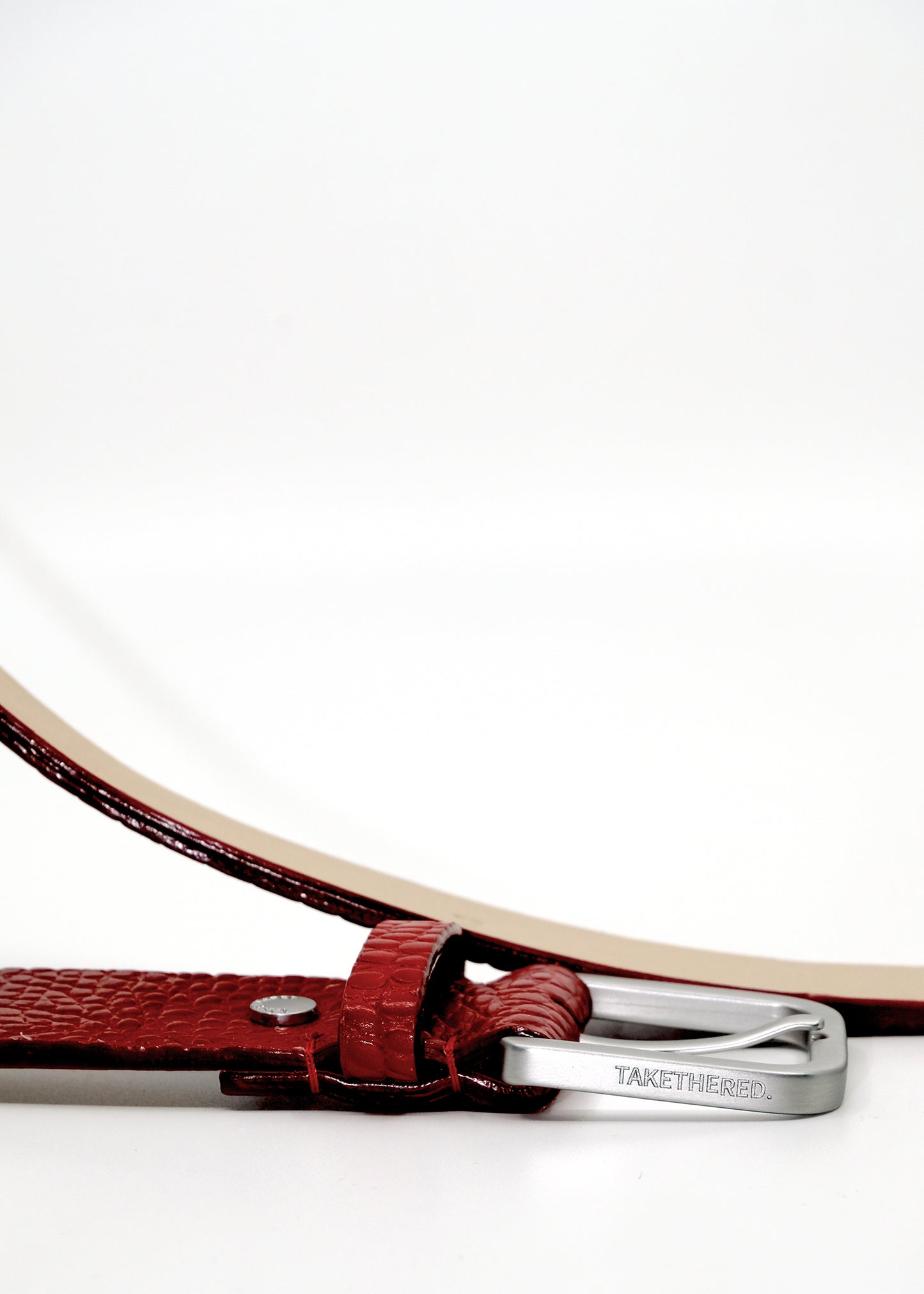 Side view of the Blood red Mississippi Belt buckle in silver metal, engraved with the "BIRD & ASH" brand name.