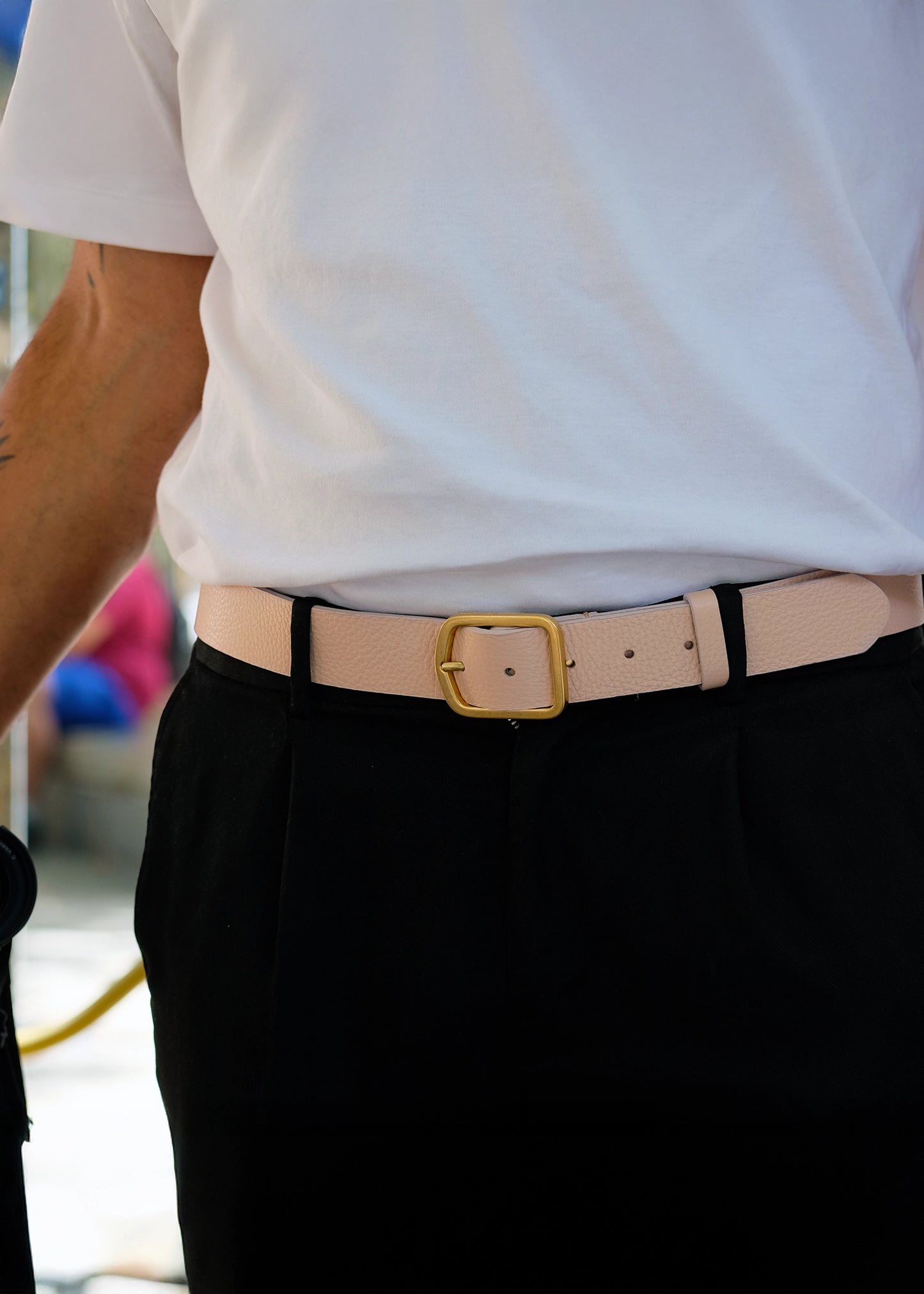 Lifestyle shot of the Nude Pink Grunge Belt worn with black pleated trousers and a white t-shirt.
