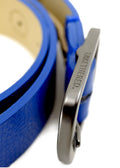 Close-up of a matte black buckle engraved with "BIRD & ASH." on a vibrant Betty Blue pebble-grain leather belt.