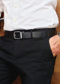 Lifestyle shot of the Pitch Black alligator-embossed Two-Face Belt worn with black pants and a striped shirt.