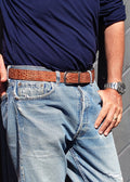 Lifestyle shot of the Two-Face Belt’s Smokey Cognac crocodile side worn with light blue jeans and a navy shirt.