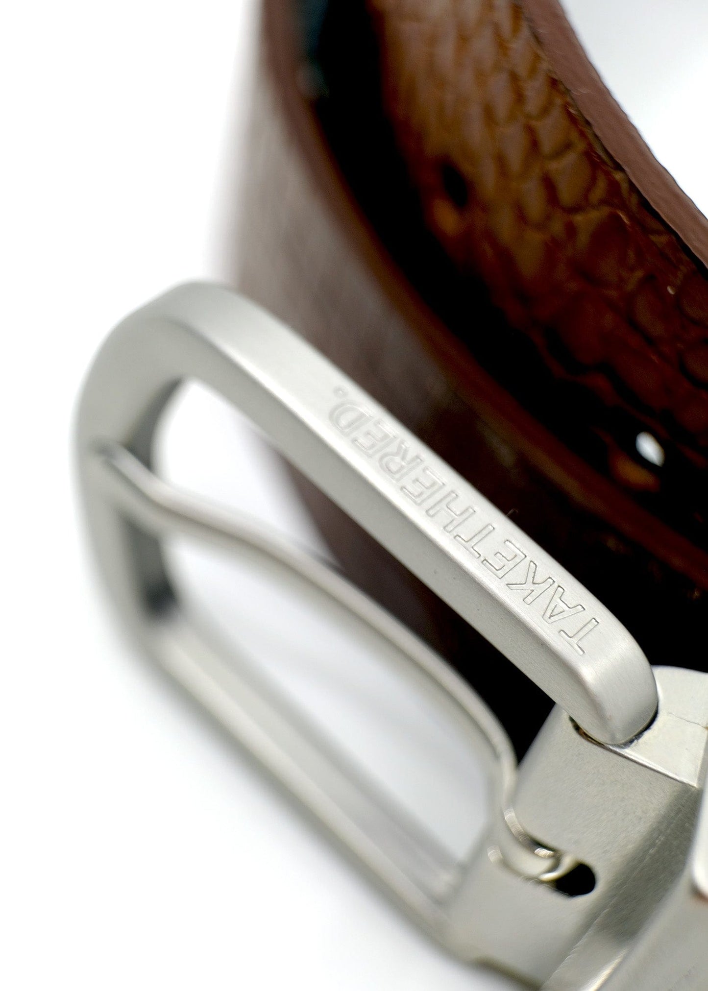 Extreme close-up of a reversible silver buckle with "BIRD & ASH." engraved on the edge, featuring Smokey Cognac crocodile leather.