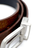 Extreme close-up of a reversible silver buckle with "BIRD & ASH." engraved on the edge, featuring a coiled belt.