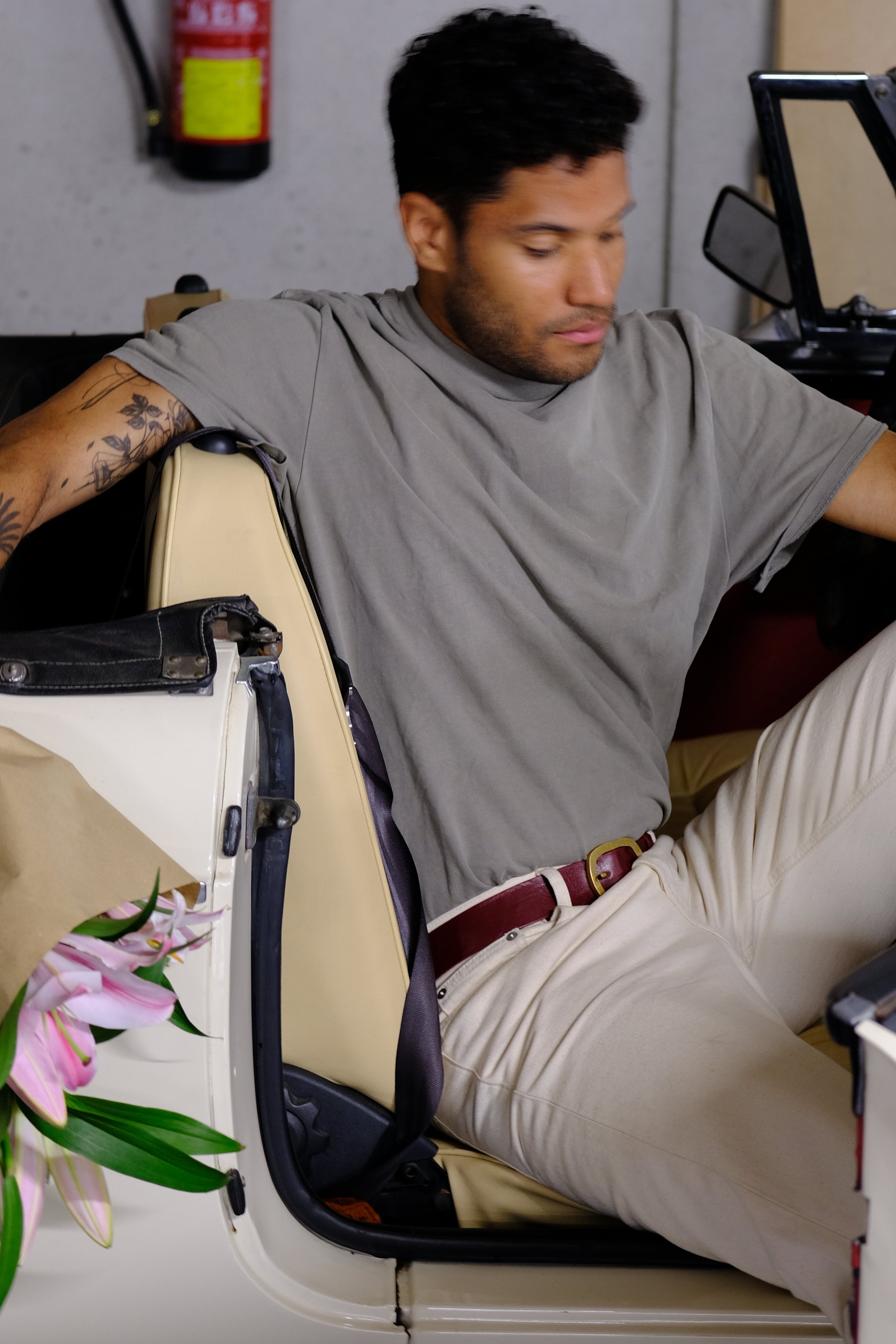 Man in a vintage sports car is wearing white denim and a Red Mist Classic Belt