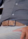 Lifestyle shot of the tan alligator-embossed Desert Sand Mississippi Belt worn with beige trousers and a grey shirt.