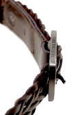 Macro shot of Espresso braided leather belt showing the side of the matte black buckle with "BIRD & ASH." engraving.