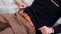 A close-up of a man's waist while he is resting on a stair wearing a Tatooine sunset orange leather belt.
