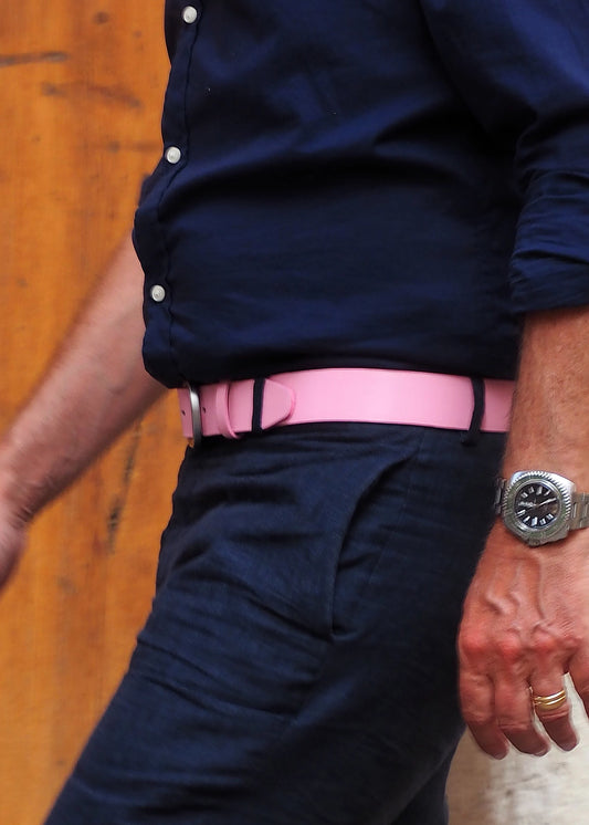 Lifestyle shot of a person wearing the Classic Barbie Pink leather belt with dark navy trousers and a blue shirt.