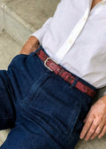 Pink snakeskin belt with a silver buckle, styled on dark blue denim with a white button-down shirt.