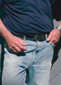 Lifestyle shot of the Two-Face Belt’s black leather side worn with light blue jeans and a navy shirt.
